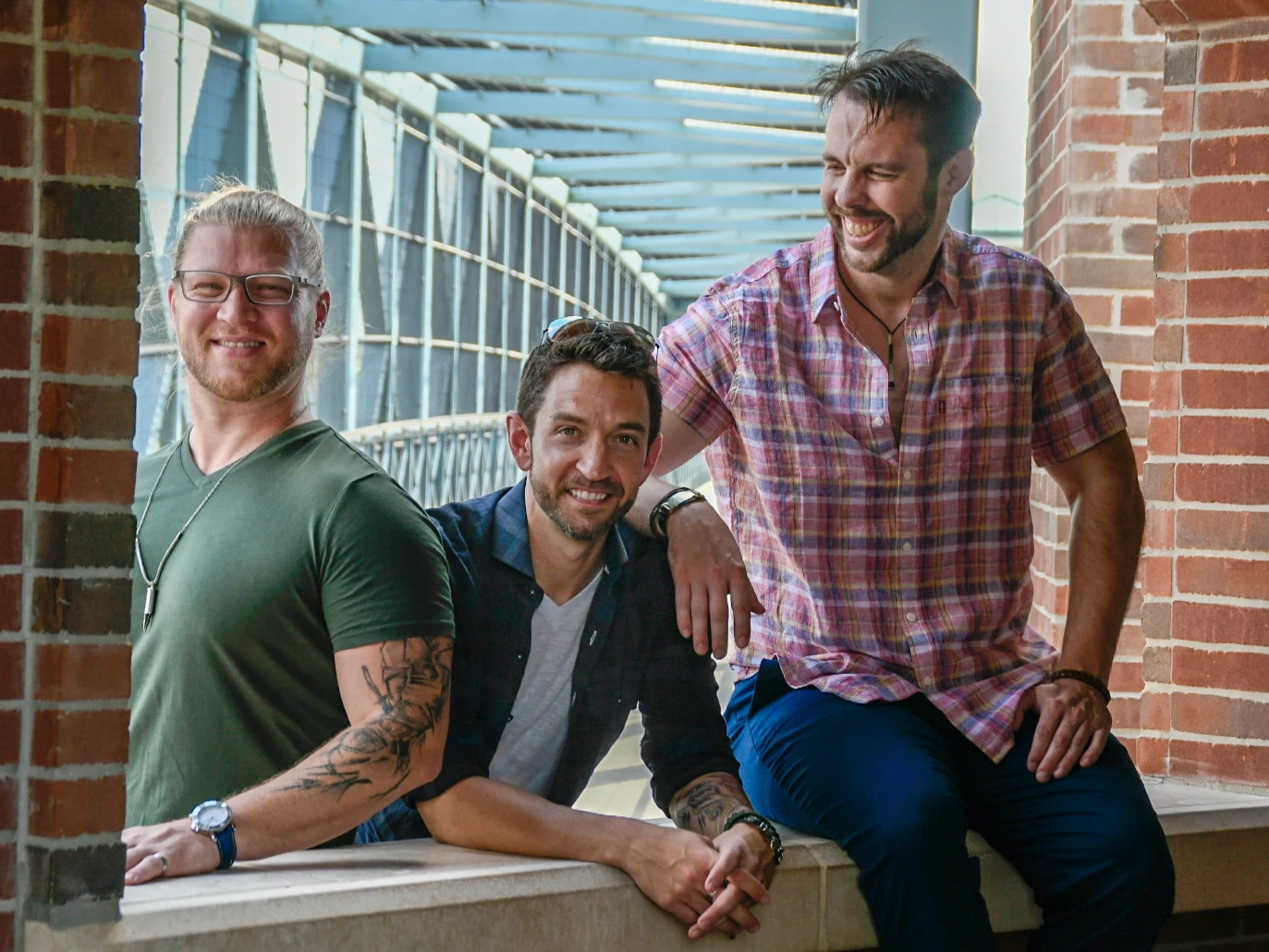 Tyler Walls, Jeff Grider, and Chris Rupp, from left to right, on a sunlit walkway